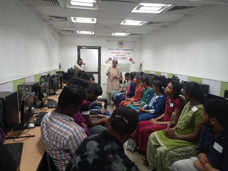 Participants sitting in two columns with trainer standing in front and speaking to them